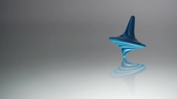 La toupie bleue tourne, vacille et s'arrête. Whirligig en action se reflète sur la surface du miroir. Mouvement lent 