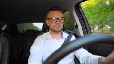 Güneşli havalarda araba kullanan gözlüklü ve beyaz gömlekli sakallı adam