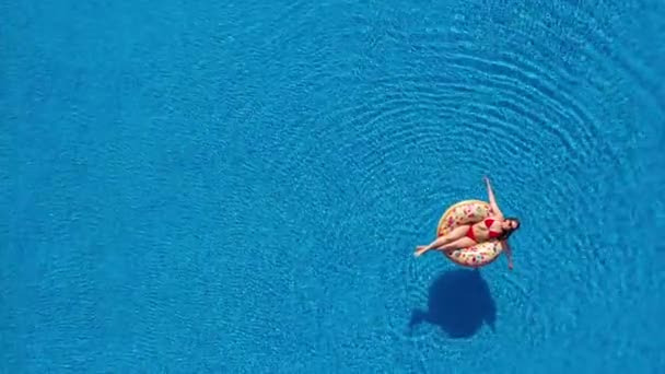 Vista aérea de una mujer en bikini rojo acostada en una dona en la piscina — Vídeos de Stock