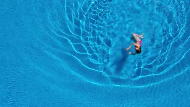 Kırmızı mayo giymiş, yüzen ve havuzda sırtüstü yatan bir kadın olarak tepeden bak. Rahatlatıcı kavram — Stok video