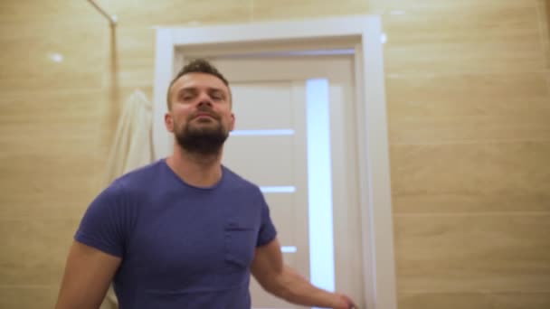 Bearded man enters the bathroom and looks at his face in the mirror. Morning routine and hygiene — Stock Video