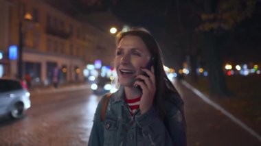 Akşamları sokaklarda yürürken akıllı telefondan konuşan çekici bir kadın.