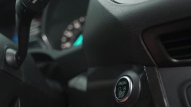 Erkek el, modern bir arabanın içinde motoru çalıştırma düğmesine basar.