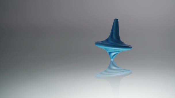 Blue spinning top spinning. Whirligig in action is reflected on mirror surface. Slow motion — Stock Video