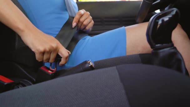 Kobieta w niebieskiej sukience zapięcie pasów bezpieczeństwa samochodu podczas siedzenia wewnątrz pojazdu przed jazdą — Wideo stockowe