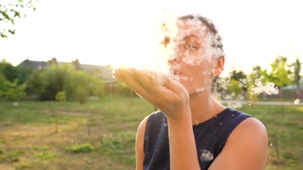 Retrato de mulher bonita sopra em juncos ao ar livre em dia ensolarado. Fluff de juncos voa ao redor. Movimento lento — Vídeo de Stock