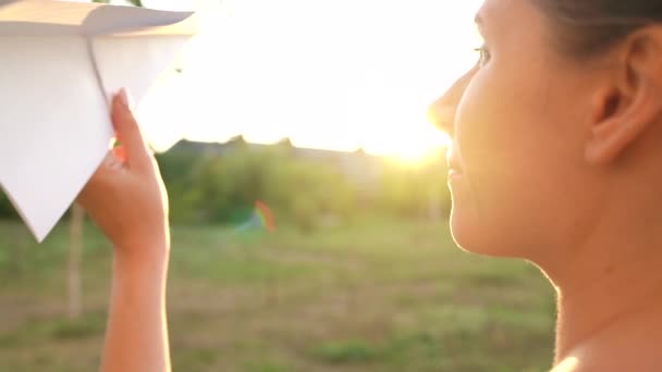 Woman launches paper airplane against sunset background. Dreaming of traveling or the profession of a stewardess. Slow motion — Stock Video