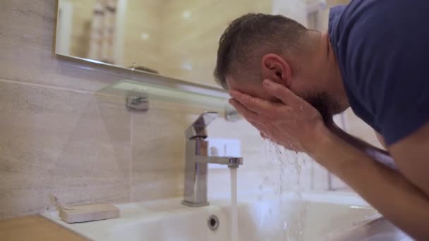 Morgenhygiene. Mann wäscht sich sein Gesicht im Badezimmer mit sauberem Wasser Zeitlupe — Stockvideo