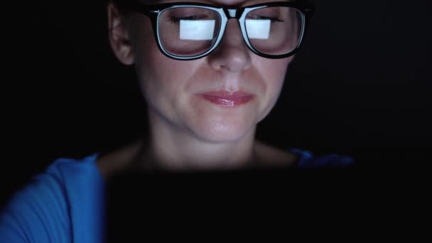 Wanita berkacamata bekerja di belakang laptop di malam hari. Pantau layar dipantulkan dalam gelas — Stok Video