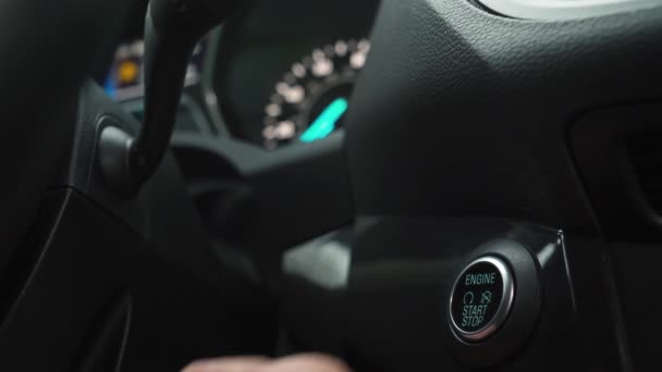 Mies käsi painaa moottorin käynnistyksen pysäytyspainiketta nykyaikaisessa auton sisustuksessa — kuvapankkivideo