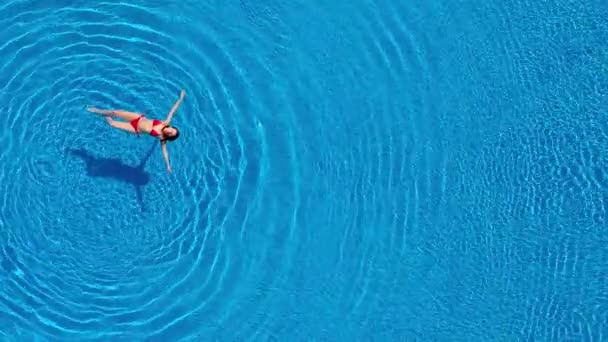 Vista de cima como uma mulher de fato de banho vermelho deitada de costas na piscina. Conceito relaxante — Vídeo de Stock