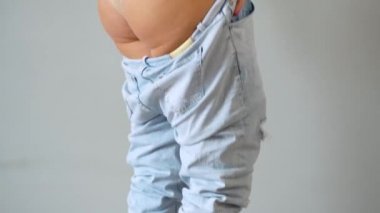 Kadın kotunu kalçasına çekiyor. Deride zar zor görülebilen selülit.