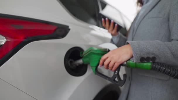 Mujer usando smartphone mientras su coche está repostando. Movimiento lento — Vídeo de stock