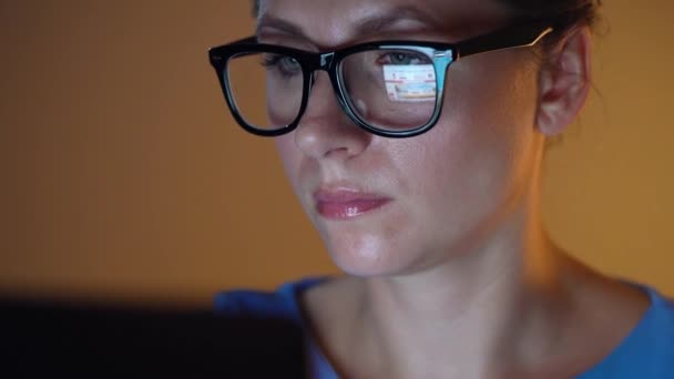 Vrouw in glazen kijkend op de monitor en surfen op Internet. Het beeldscherm wordt weerspiegeld in de glazen — Stockvideo