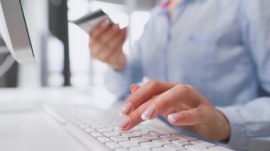 Bilgisayar klavyesinde kredi kartı numarası yazan kadın eller. İnternetten alışveriş yapan bir kadın. Çevrim içi ödeme servisi.