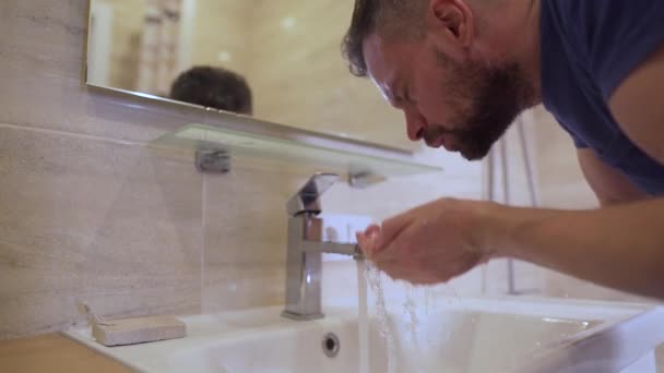 Morgenhygiene. Mann wäscht sich sein Gesicht im Badezimmer mit sauberem Wasser Zeitlupe — Stockvideo