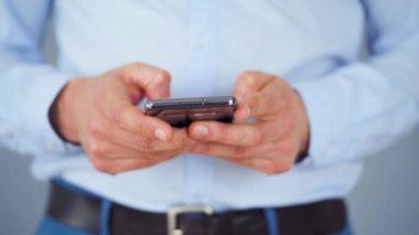 Resmi olarak giyinmiş bir adam internete yakın çekim yapmak için akıllı telefon kullanıyor.