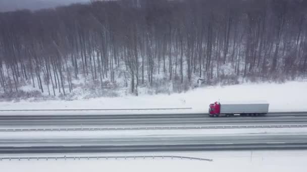 Vista aérea del tráfico en una carretera rodeada de bosque de invierno en las nevadas — Vídeos de Stock