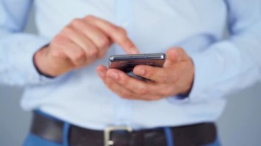 Resmi olarak giyinmiş bir adam internete yakın çekim yapmak için akıllı telefon kullanıyor.