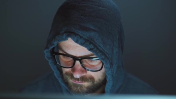 头罩里的男性黑客和眼镜在一间黑暗的办公室的电脑上工作。 网络犯罪概念 — 图库视频影像