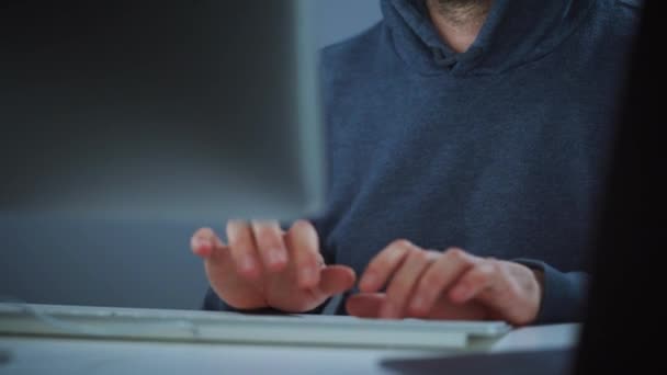 Kapüşonlu ve gözlüklü bir erkek hacker karanlık bir ofis odasında bilgisayar üzerinde çalışıyor. Siber suç kavramı — Stok video