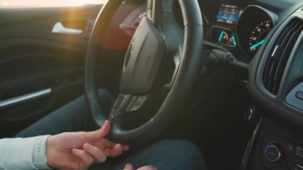 Close up of a man steers a car. Sunlight shines through the side window. — Stock Video