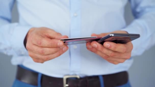 Formally dressed man selects a credit card from several and enters it number into a smartphone to pay online. Online shopping, lifestyle technology. Close-up — Stock Video