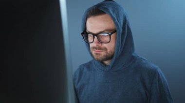 Kapüşonlu ve gözlüklü bir erkek hacker karanlık bir ofis odasında bilgisayar üzerinde çalışıyor. Siber suç kavramı