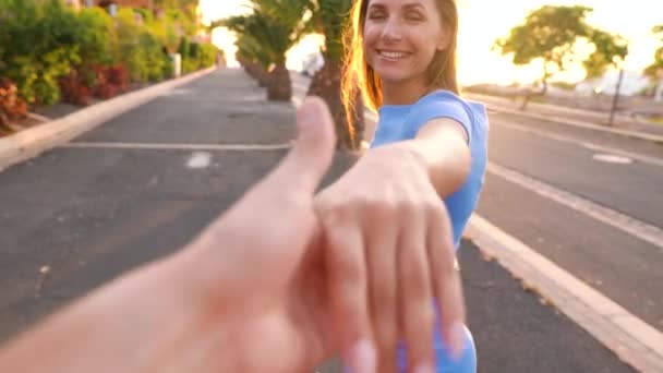 Två i en video. Följ mig - lycklig kvinna sträcker ut sin hand till mannen, han tar hennes hand försiktigt — Stockvideo