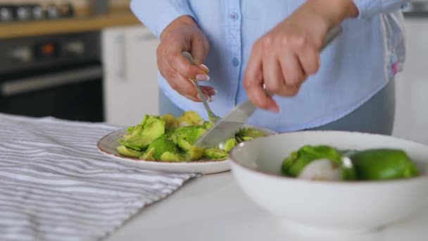 Vrouw hakken avocadoon op de plaat om gezond veganistisch ontbijt te maken — Stockvideo