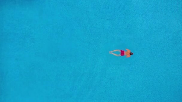 Aerial view of man in red shorts swims in the pool. Slow motion — 비디오