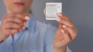 Kadın elleri kameradan önce prezervatif gösteriyor. Güvenli seks, doğum kontrolü.