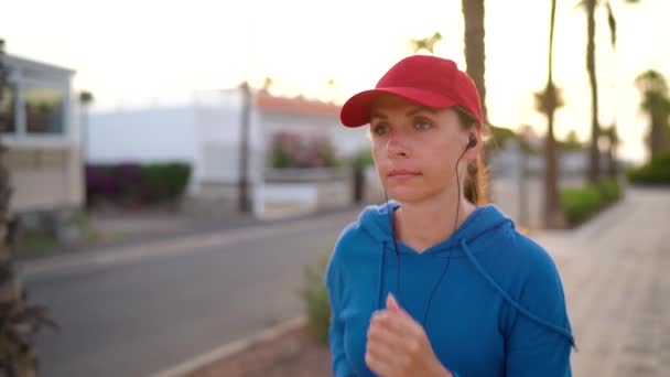 Kadın gün batımında Palm Bulvarı boyunca caddede koşuyor. Sağlıklı aktif yaşam tarzı. Yavaş çekim — Stok video