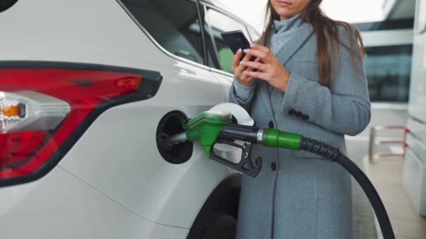 Kobieta używająca smartfona podczas tankowania samochodu. Zwolniony ruch — Wideo stockowe