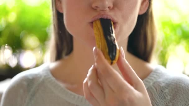 Mujer come eclair de chocolate en un café de cerca — Vídeos de Stock