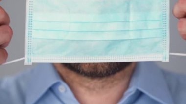 Covid-19 koronavirüsünün pandemik koruması. Tıbbi maske takmış sakallı beyaz bir adamın portresi. Virüs koruması.