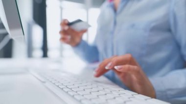 Kadın kredi kartı numarasını bilgisayar klavyesinden giriyor. İnternetten alışveriş yapan bir kadın. Çevrim içi ödeme servisi.