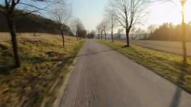 FPV insansız hava aracı hızlı ve manevra kabiliyetli kırsal bir yolda uçuyor ve gün batımında güç döngüsü yaratıyor.