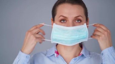 Covid-19 koronavirüsünün pandemik koruması. Tıbbi maske takan beyaz bir kadın. Virüs koruması.