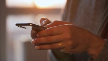 Batan güneşe karşı akıllı telefon kullanan kadın eller..
