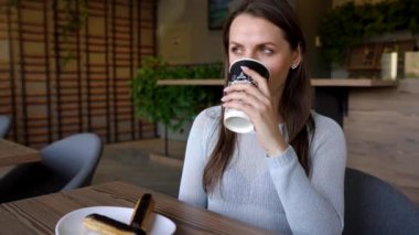 Çikolatalı pasta yiyen ve kafede kahve içen bir kadın.