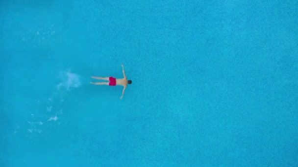 Blick von oben, als ein Mann in den Pool eintaucht und unter Wasser schwimmt — Stockvideo