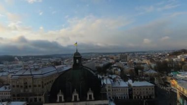 FPV insansız hava aracı gün batımında Lviv Opera ve Bale Tiyatrosu 'nun çatısında uçar. Çerçevenin ortasında Ukrayna bayrağı var. Lviv 'in tarihi merkezinin havadan görünüşü