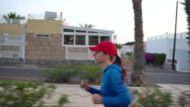 Vrouw rent de straat op. Een gezonde actieve levensstijl. Zijaanzicht — Stockvideo
