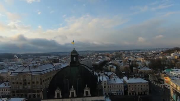 Dron FPV przelatuje nad dachem Lwowskiego Teatru Opery i Baletu o zachodzie słońca. Flaga Ukrainy w centrum kadru. Widok z lotu ptaka na historyczne centrum Lwowa — Wideo stockowe