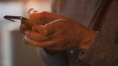 Batan güneşe karşı akıllı telefon kullanan kadın eller..