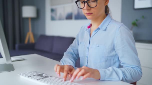 Een vrouw met een bril typt op een toetsenbord. Begrip werk op afstand. — Stockvideo