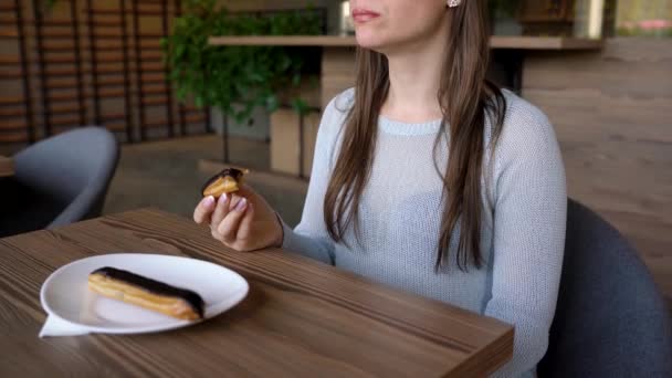 Femme mange éclair au chocolat dans un café — Video