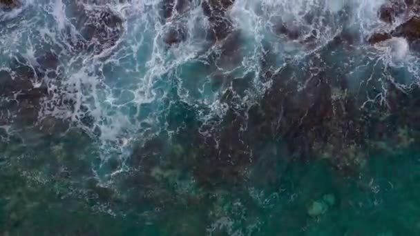 Top uitzicht op de oceaan oppervlak in de buurt van de rotsachtige kust van het eiland Tenenife, Canarische eilanden, Spanje. Luchtvaart drone beelden van zee golven bereiken Shore — Stockvideo