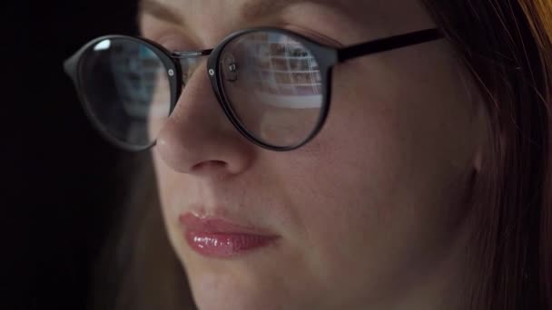 Mujer con gafas mirando en el monitor y navegando por Internet. La pantalla del monitor se refleja en las gafas. Trabaja de noche. Ministerio del Interior. Trabajo remoto — Vídeos de Stock